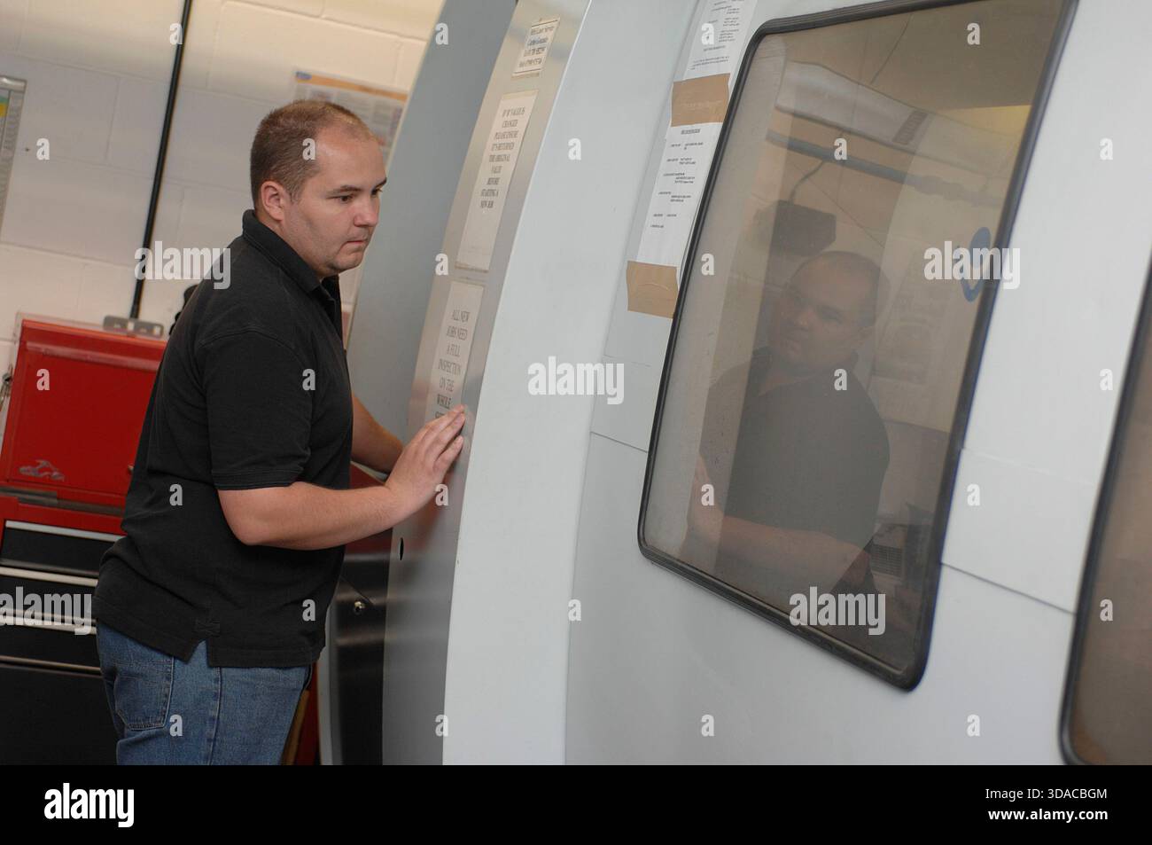 Workers guiding a computed guided lathe in an engineering factory. Stock Photo