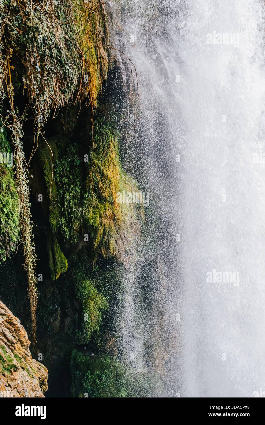 Close Up Detail of Waterfall Spray Against Mossy Rock Wall and Green Vegetation, Water and Mist Stock Photo