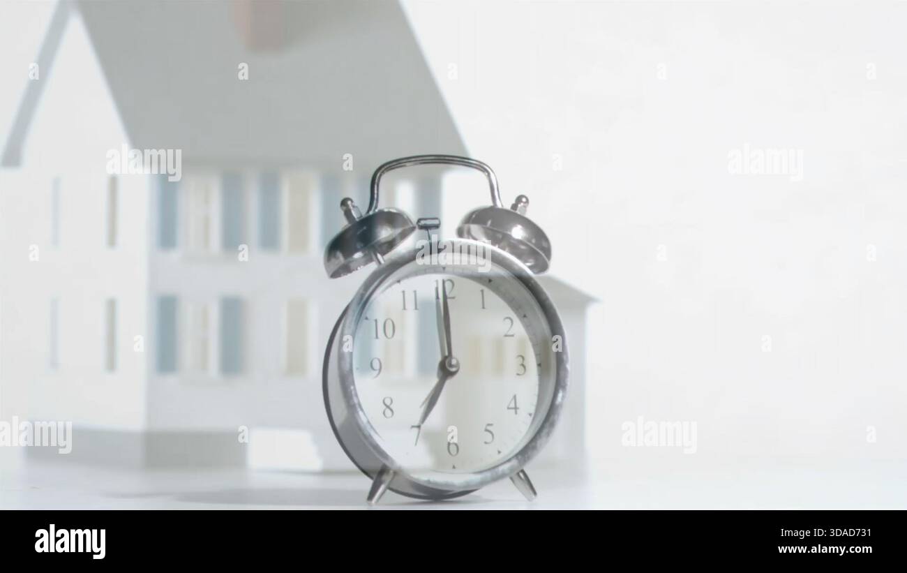 Flat design is showing silver clock sitting on white tabletop with small house, real estate theme Stock Photo