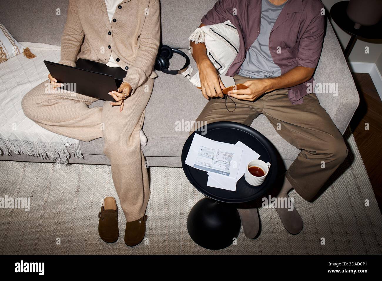 Woman Using Laptop Beside Man Reading Documents Stock Photo