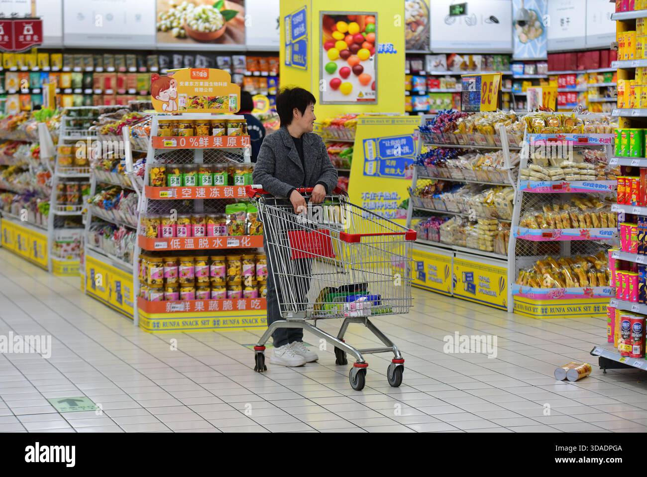 A woman pushes a shopping cart past a snack display at RT-Mart, with ...