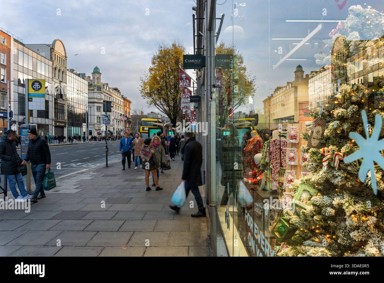 Dublin city centre at holiday time, with reflective shopfronts, festive décor, and bustling pedestrian flow. Stock Photo