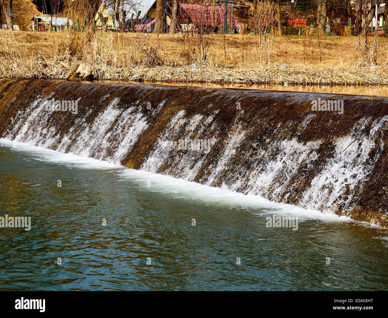 Small waterfall on a river dam with flowing water Stock Photo