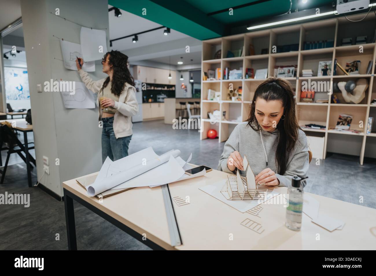 Students collaborate in a modern design studio, building architectural models and refining plans together Stock Photo