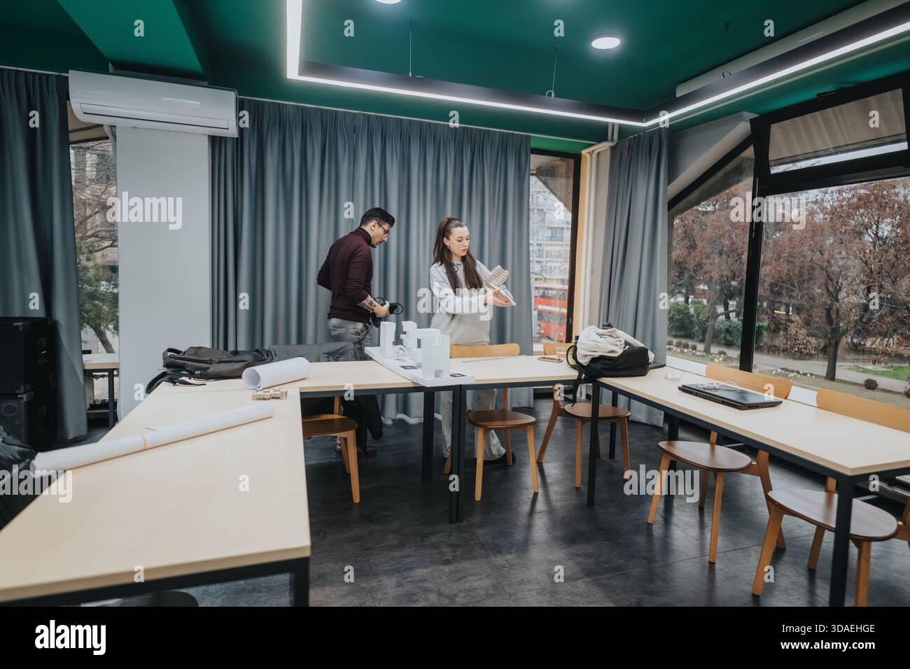 Students collaborate in a modern classroom studio, organizing plans and materials for a group project Stock Photo