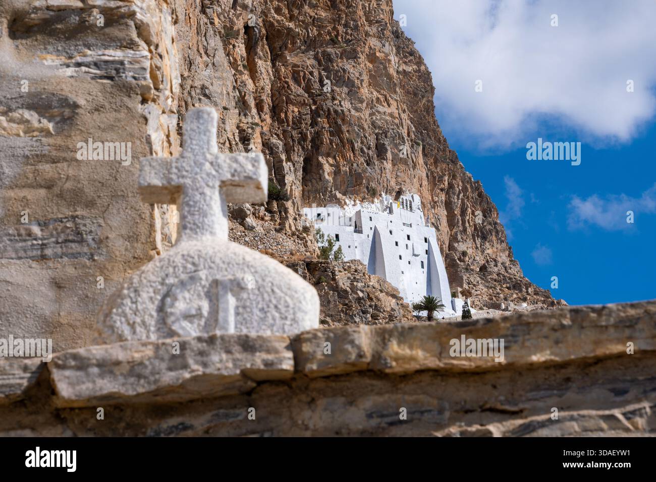 The Panagia Hozoviotissa Monastery in Amorogos, Greece, is visible with a large religious cross situated prominently in the foreground Stock Photo