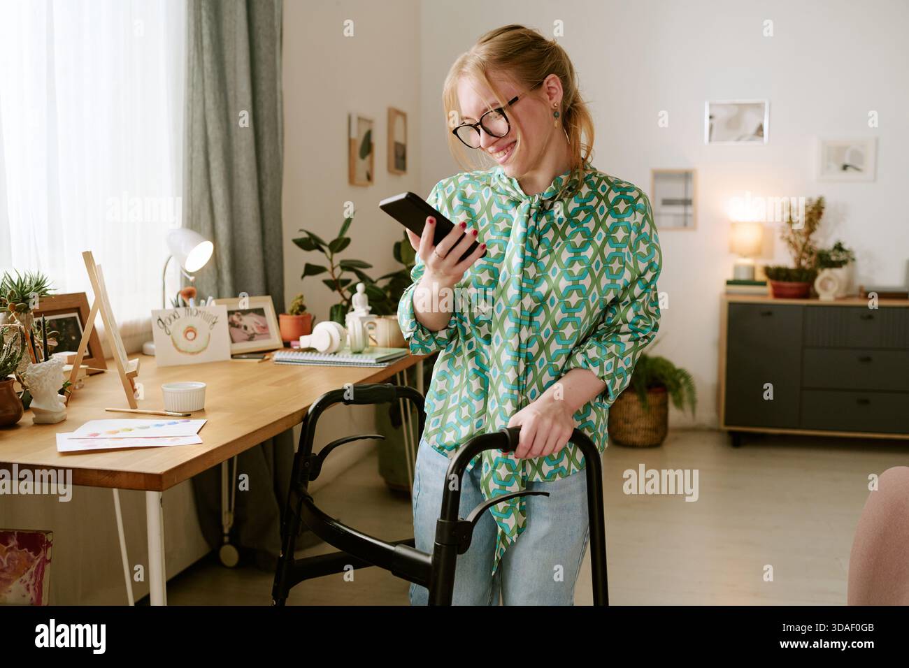 Young Woman with Disability Smiling While Using Smartphone Indoors Stock Photo