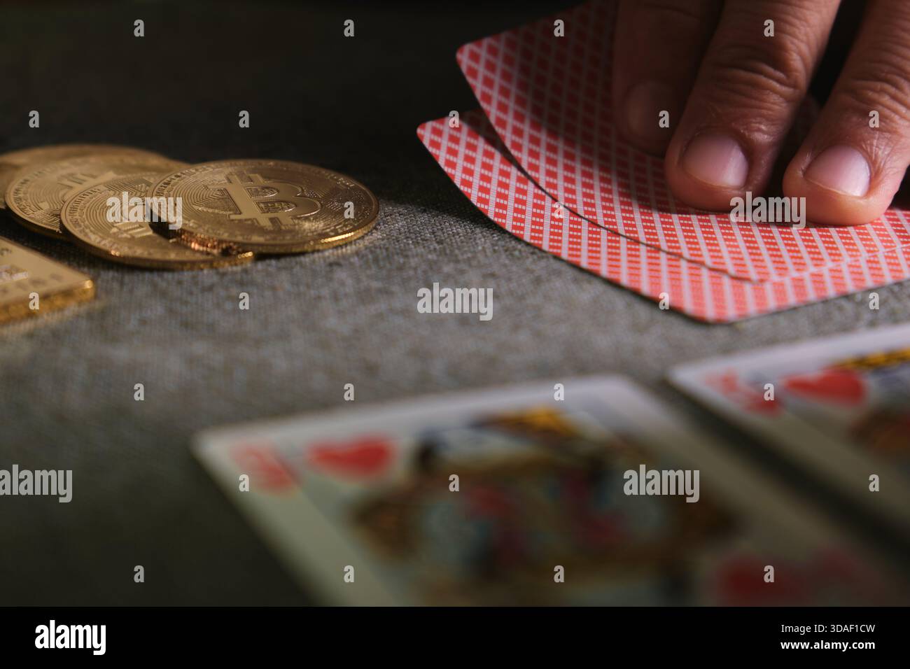 Hand holding playing cards near golden bitcoins on a table, symbolizing  risk and crypto gambling Stock Photo - Alamy