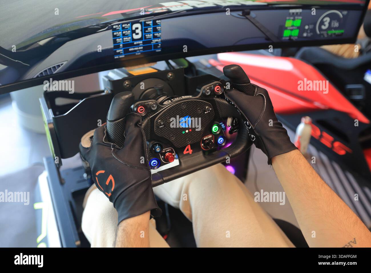 Players participate in a race in the racing car driving simulator at the Marco Simoncelli World Circuit. Detail of the driving steering wheel. - Stock Image