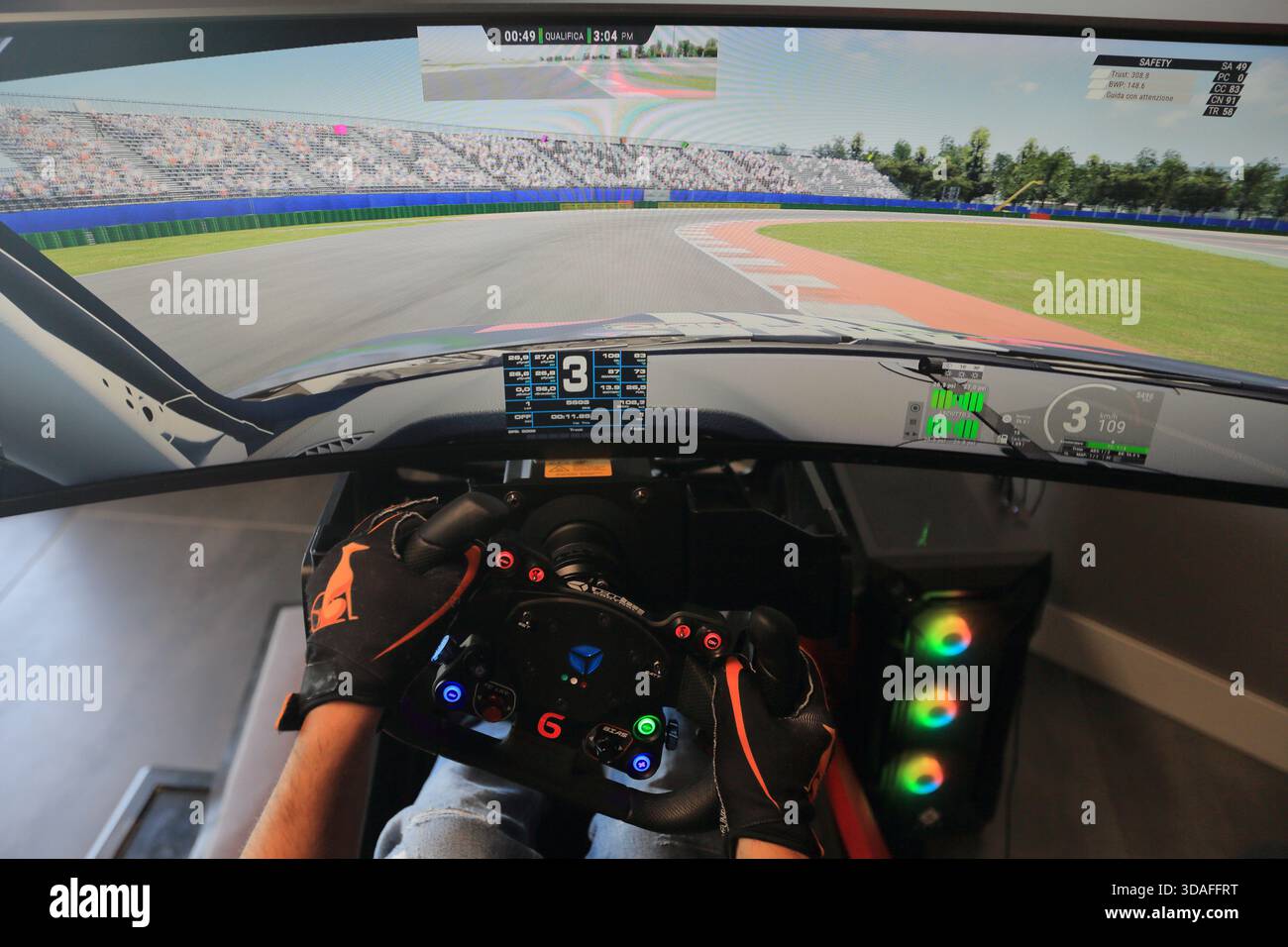 Players participate in a race in the racing car driving simulator at the Marco Simoncelli World Circuit. Detail of the driving steering wheel. - Stock Image