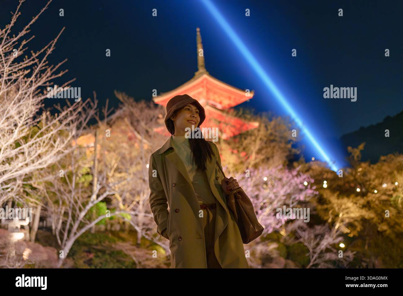 Asian woman enjoying and posing in front of illuminated wooden pagoda of Kiyomizudera temple during night light up in Kyoto, Japan Stock Photo