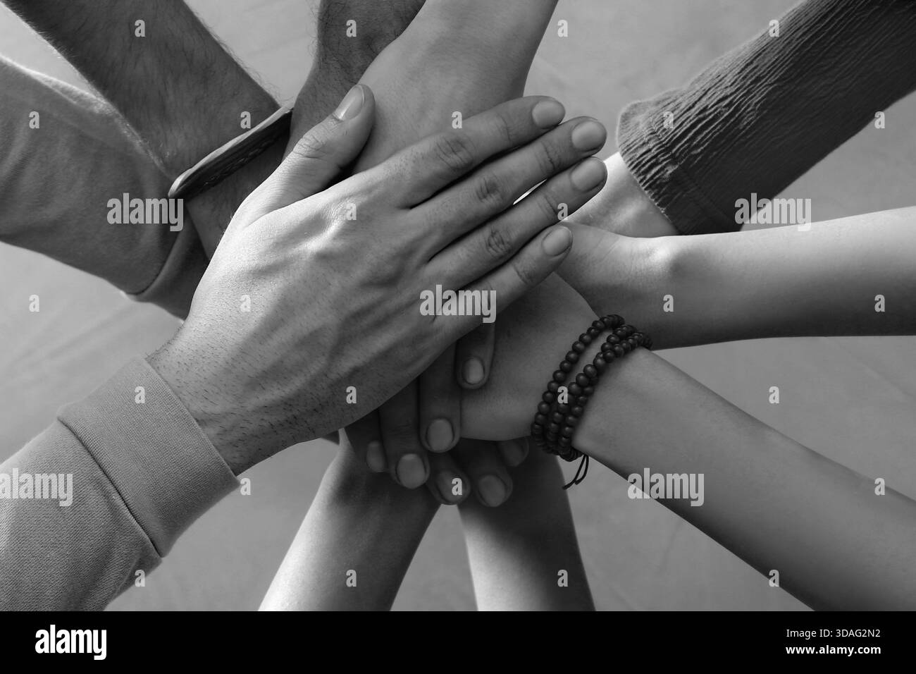 Group of people stacking their hands together, top view. Black-and ...