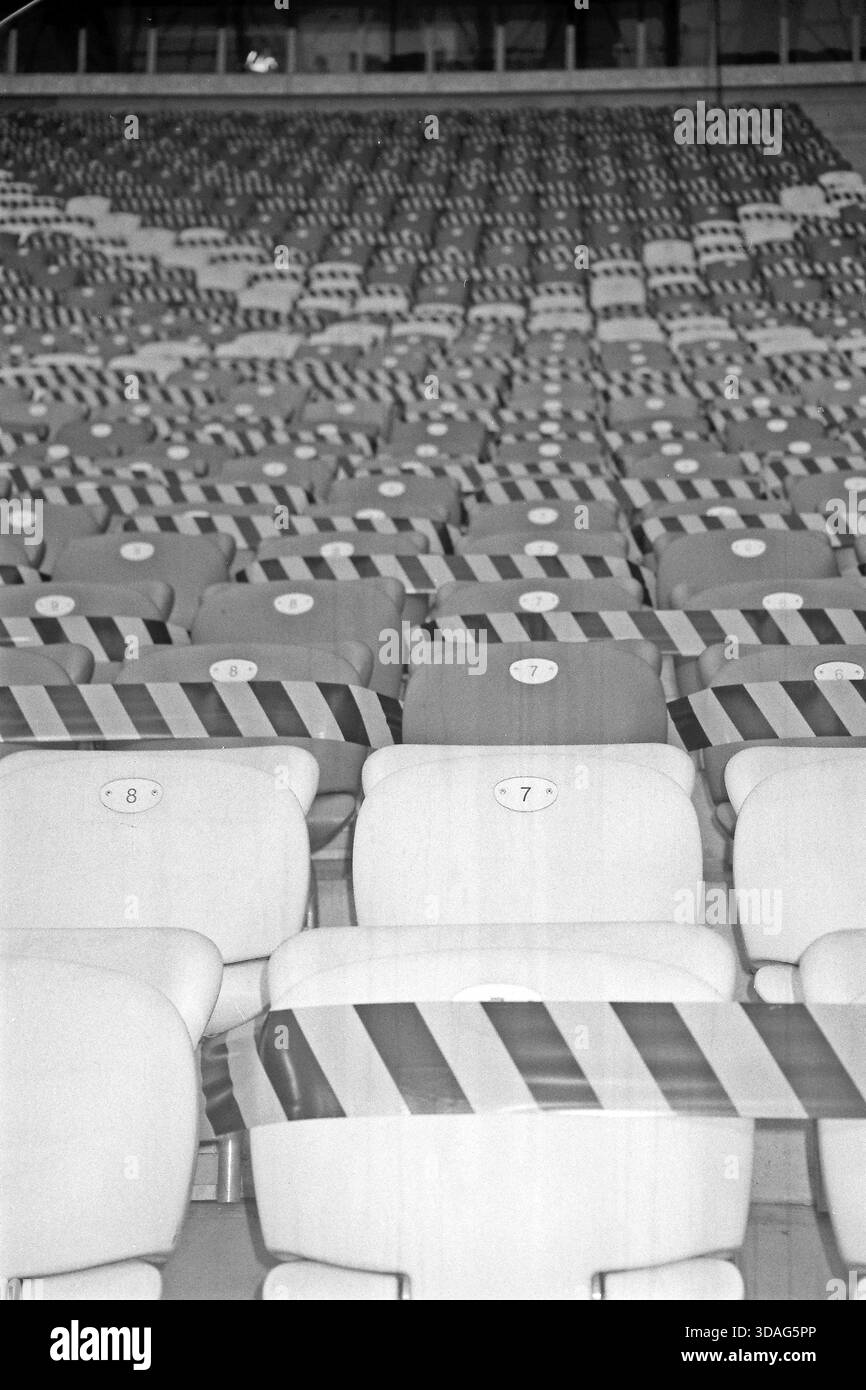 Black and white analog photo of stadium seats marked with tape during the COVID-19 pandemic to prevent use. Stock Photo