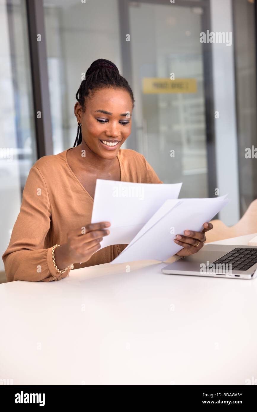 Positive young Black business professional woman reading documents Stock Photo