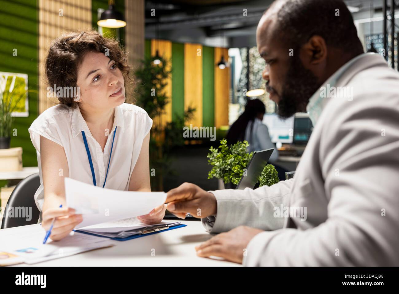 Female HR recruiter speaking with black man job seeker in office, discussing CV resume feedback during formal interview, asking questions to ensure a successful meeting for career development. Stock Photo