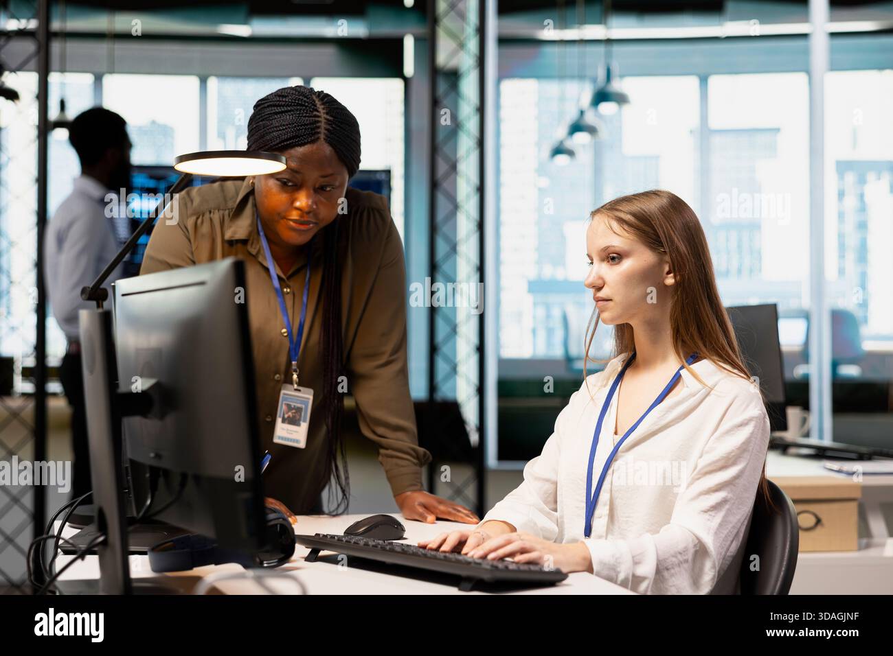 Manager supervising young employee in startup office, reviewing code scripts on computer. African american tech company supervisor overseeing work by trainee doing software development Stock Photo