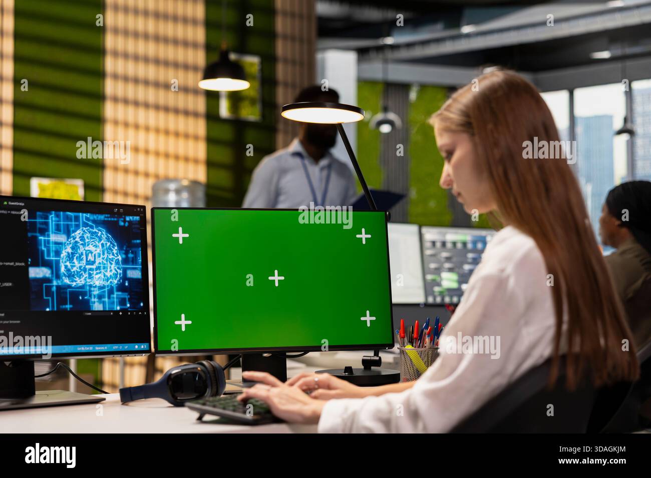 Female engineer developing applications using green screen computer, integrating AI in office systems. Worker doing internship in tech startup debugging applications using chroma key PC Stock Photo