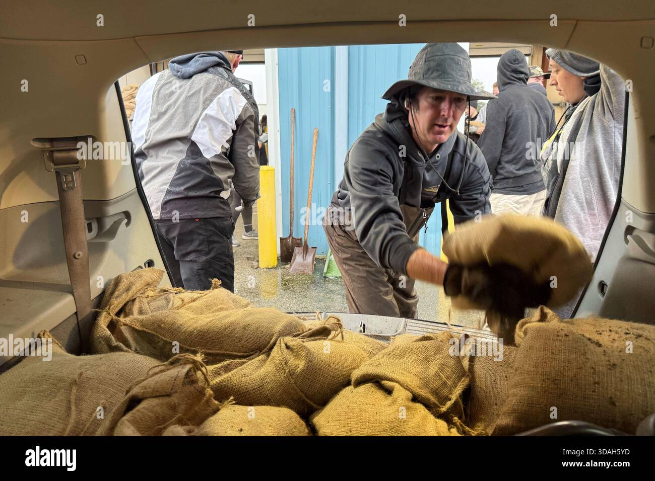 Volunteers load sandbags into a vehicle to prepare for major flooding ...