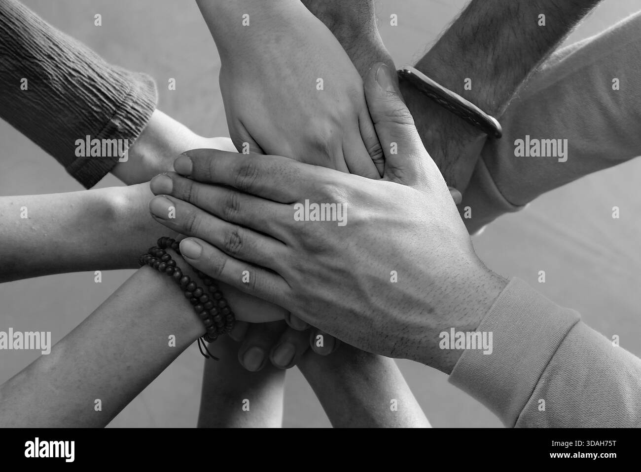 Group of people stacking their hands together, top view. Black-and ...
