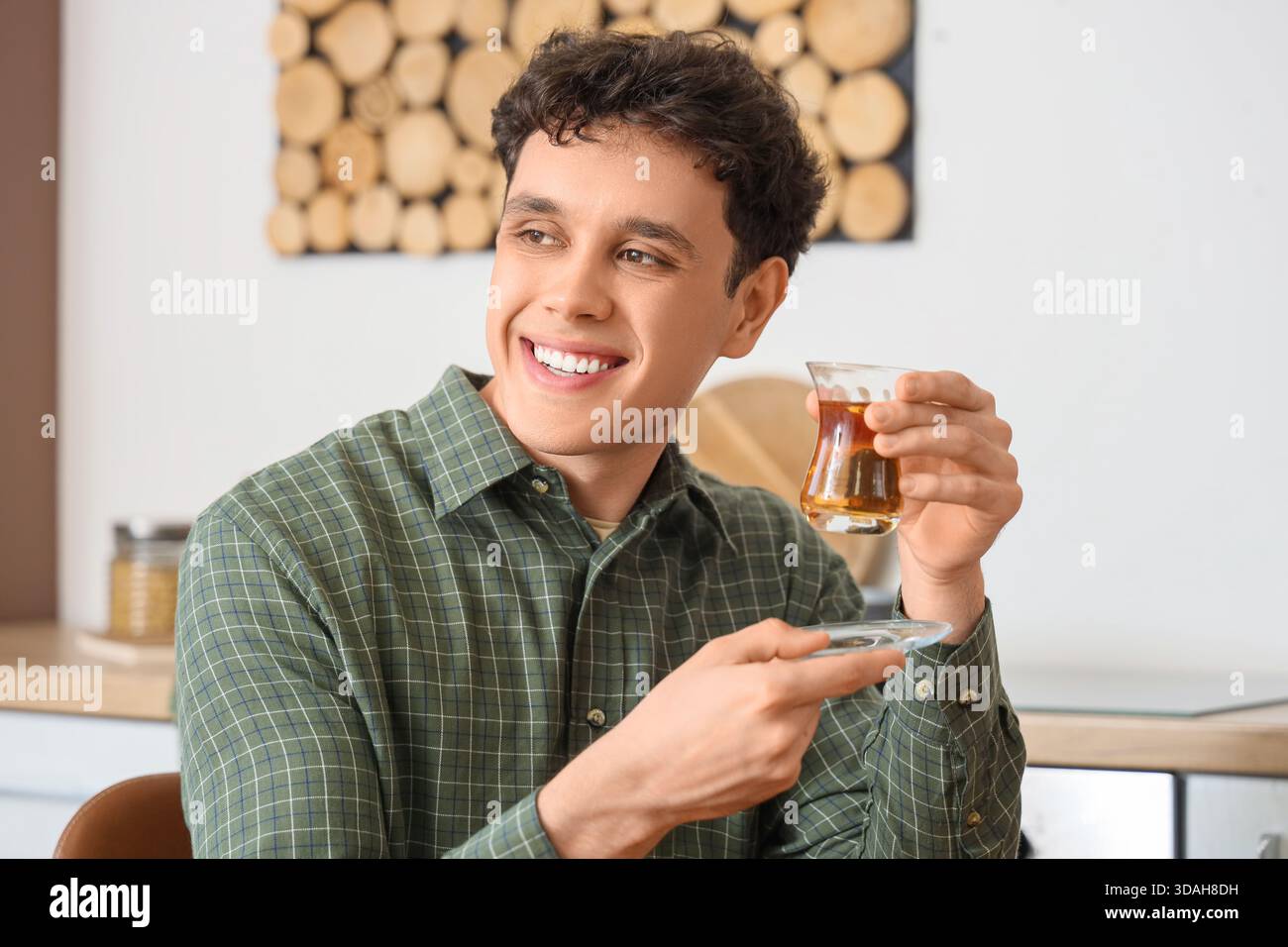 Young man with Turkish tea in kitchen Stock Photo