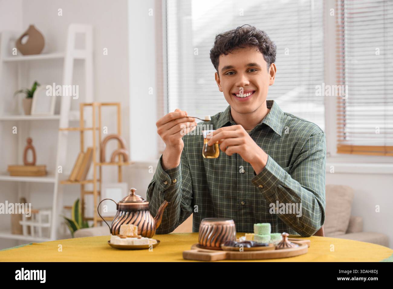 Young man with Turkish tea at table in kitchen Stock Photo