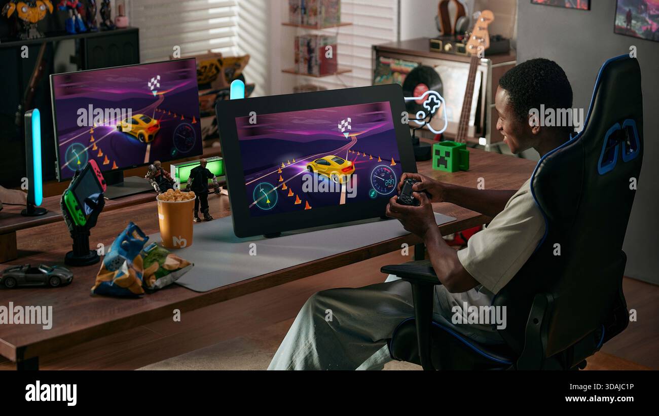 Young gamer playing racing video game on large graphics tablet screen using controller in gaming setup Stock Photo