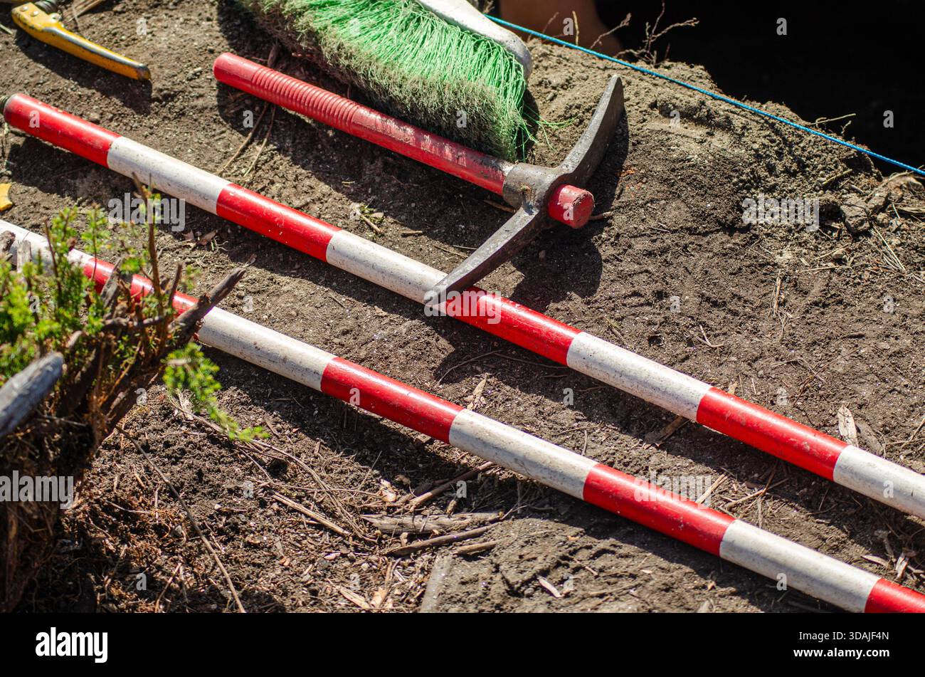 Red Striped Measuring Sticks And Pickaxe Work Site Soil Stock Photo