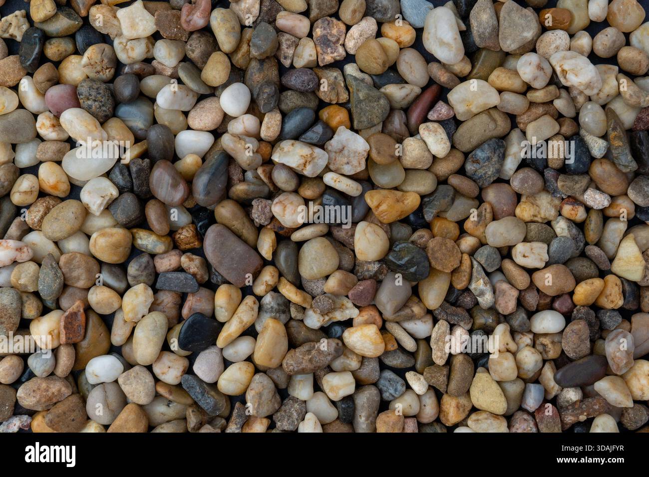 Close-up, full-frame texture shot of naturally varied, small, smooth river stones and pebbles in various colors Stock Photo