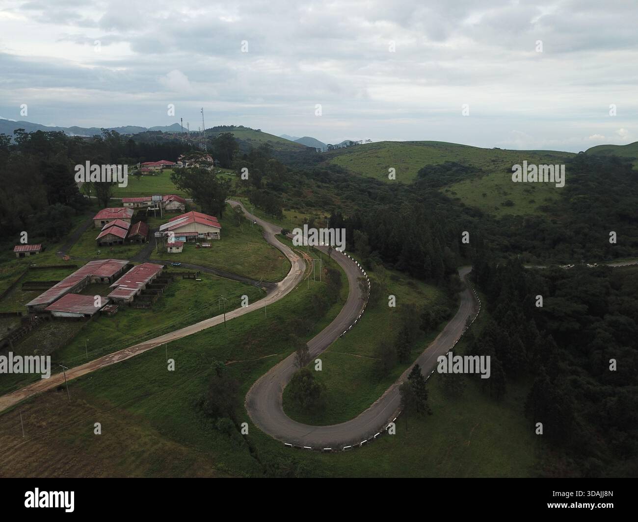Aerial view of a winding road snakes through lush green hills and ...