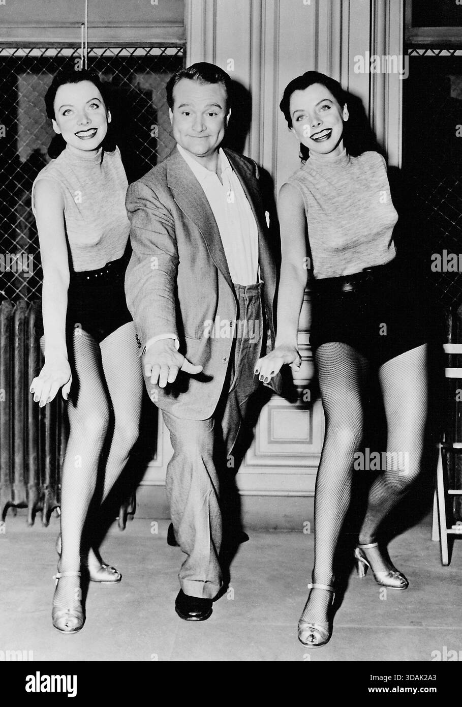 American comedian Red Skelton dances with twins Eva and Neva Martell ...