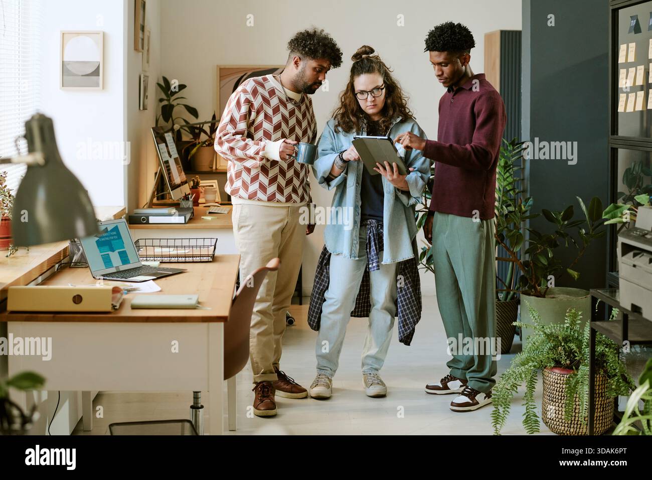 Young Multiethnic Colleagues Collaborating on Digital Tablet in Modern Office Stock Photo