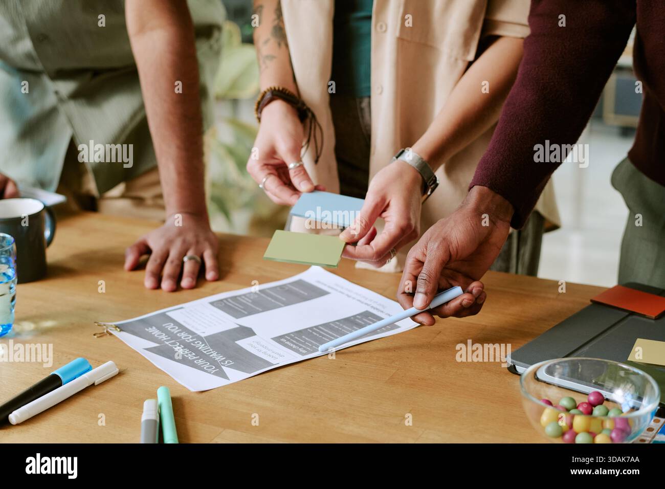 Multiethnic Young Adults Collaborating on Creative Project at Office Table Stock Photo