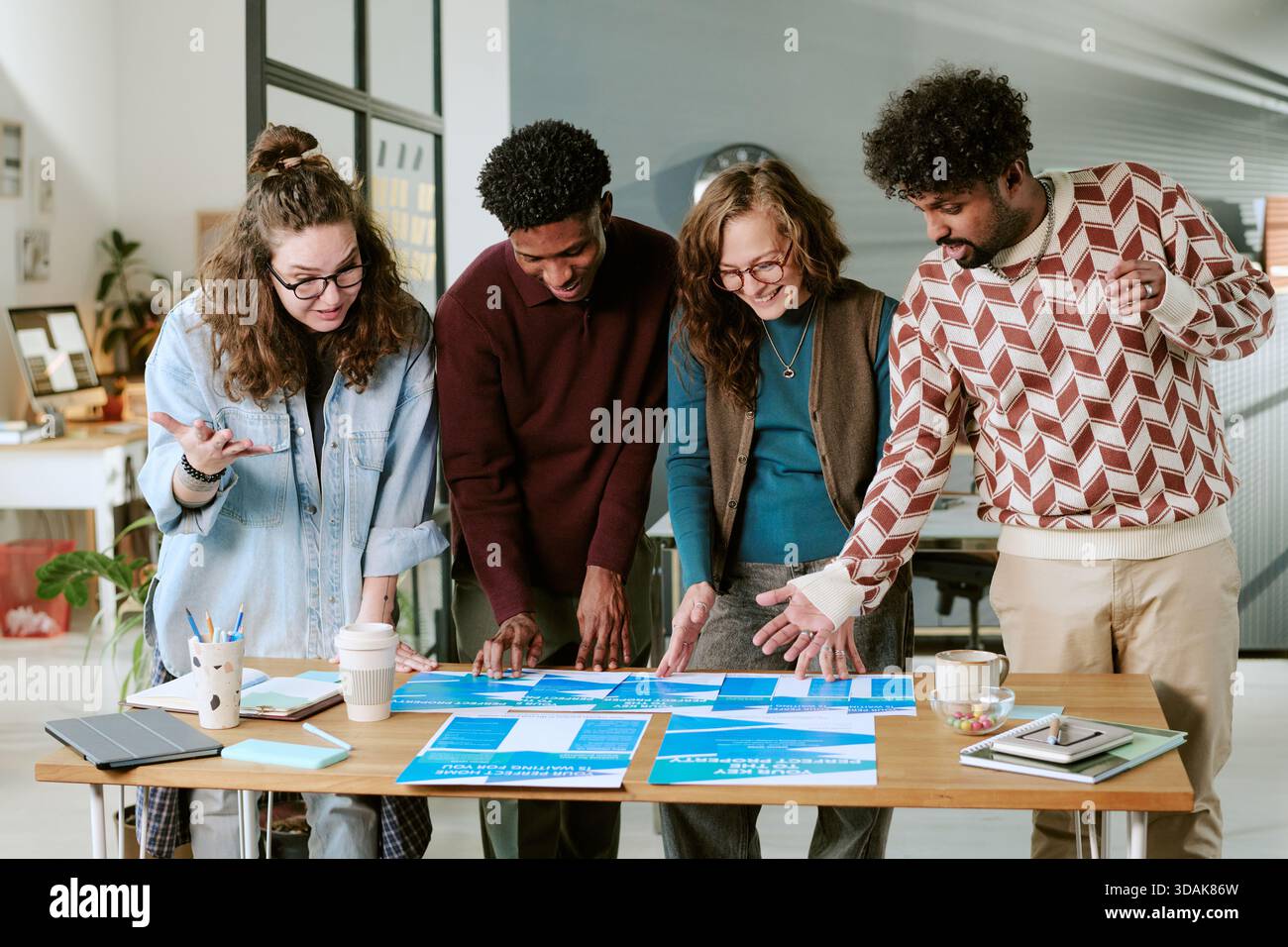 Diverse Young Adults Collaborating on Creative Project in Modern Office Setting Stock Photo