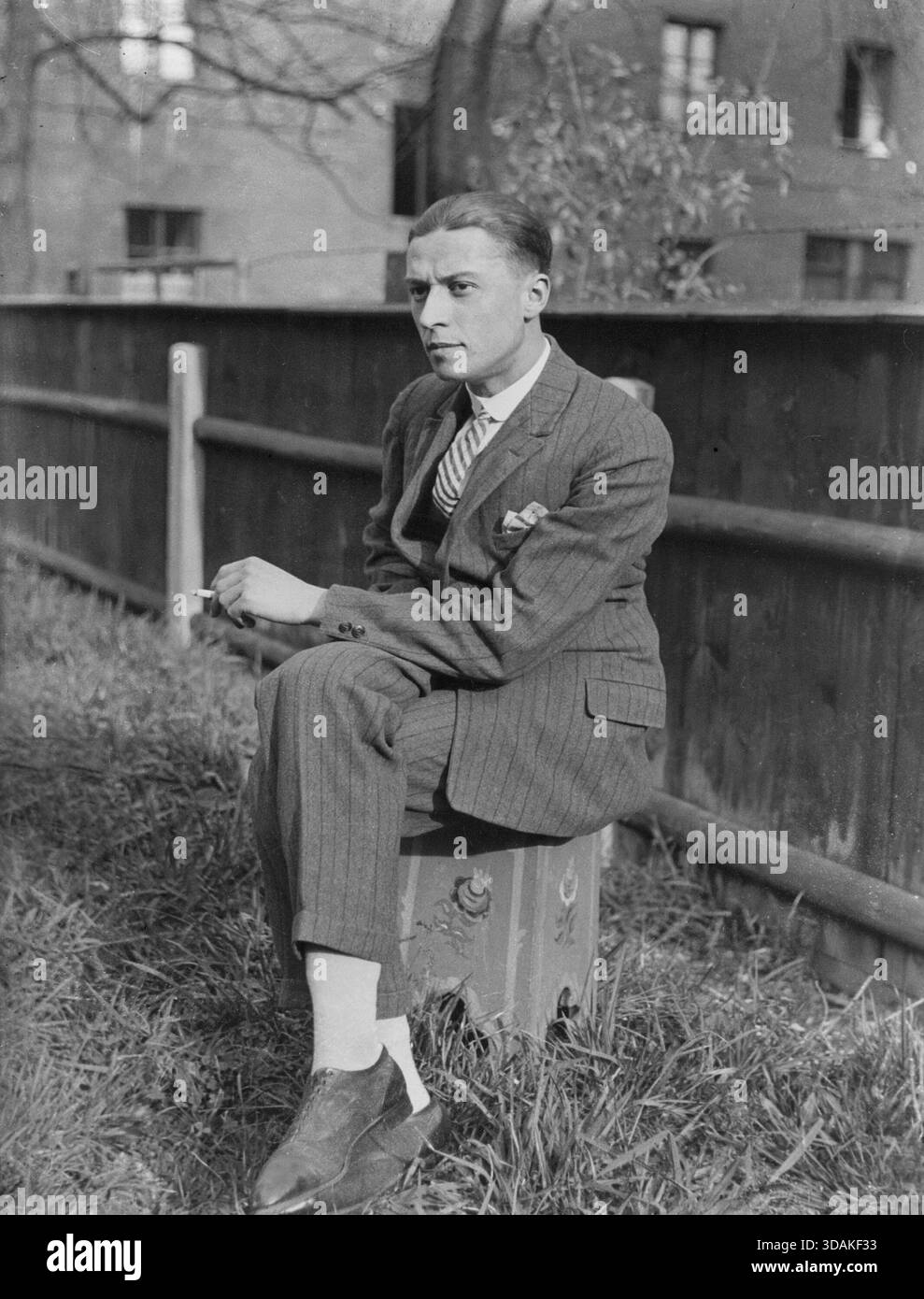 cigarette stool A man wearing a suit sits on a stool and smokes a cigarette. [automated  translation] Stock Photo