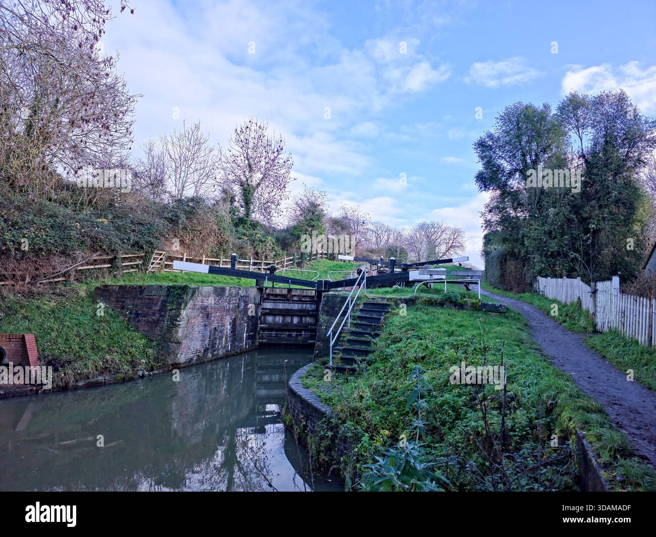 Historic double lock with wooden lock gates and white picket fence on the restored Stroudwater Canal in winter, Stroud, Cotswolds, Gloucestershire, - Smartphone Captured Stock Image