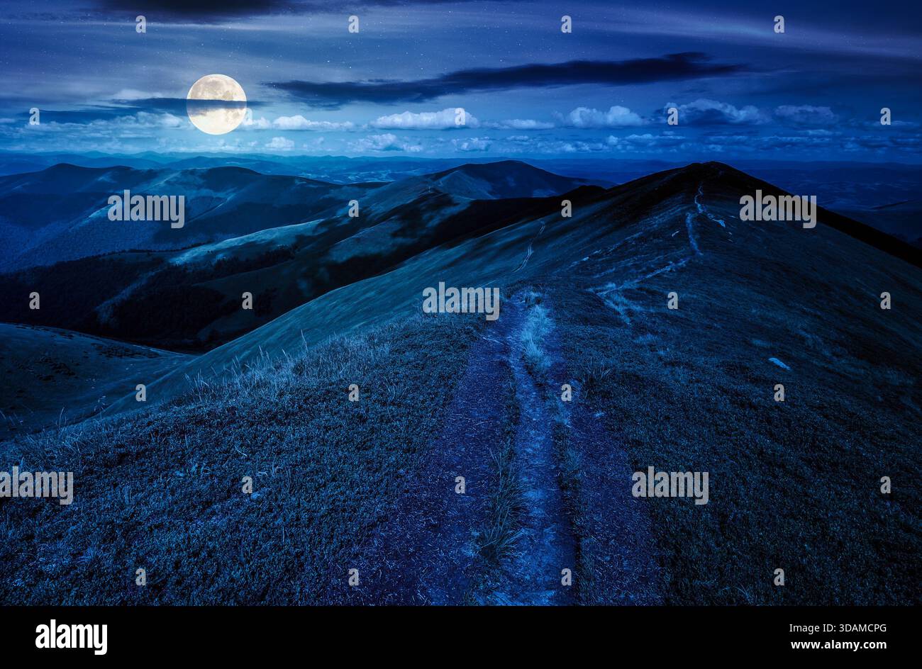 landscape with footpath on top of mountain ridge with grassy slopes at night. beautiful scenery on summer weather with clouds on sky in full moon ligh Stock Photo