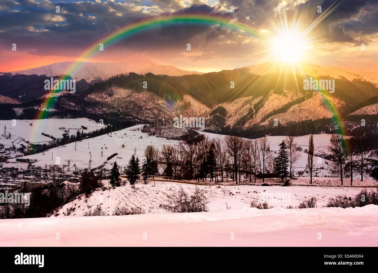 winter sky over the mountains at sunset. beautiful light on snowy tops of ridge in evening light. rural landscape with serpentine pass in to valley. l Stock Photo