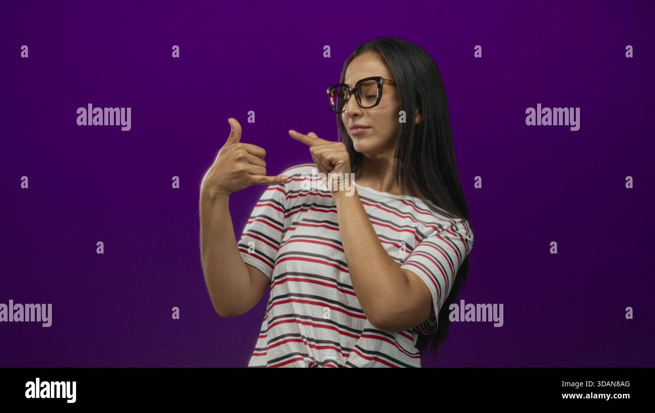 Woman finger pointing to hand in purple studio wall, showing call ...