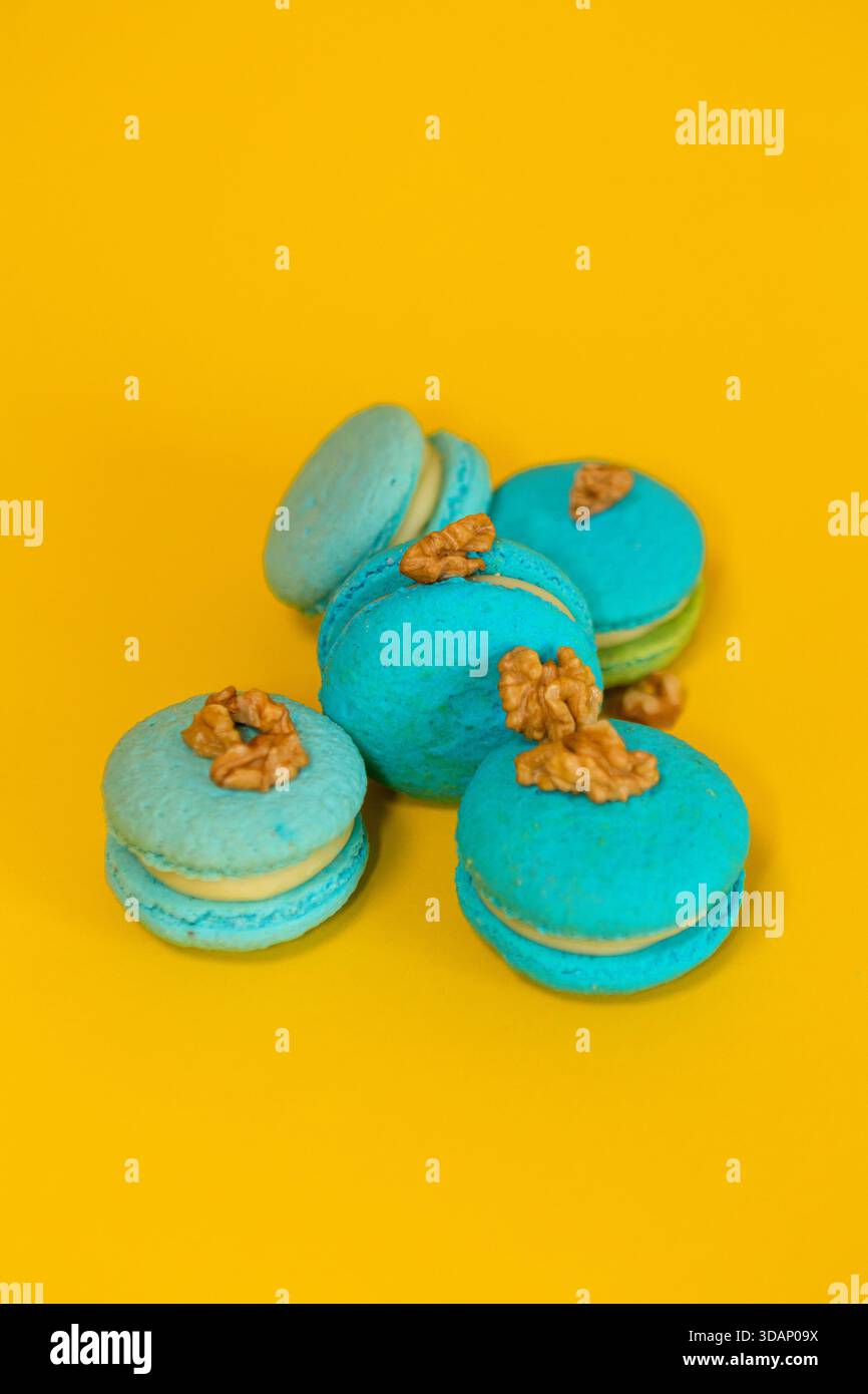 Blue macaroons on a yellow plain background, with walnuts Stock Photo