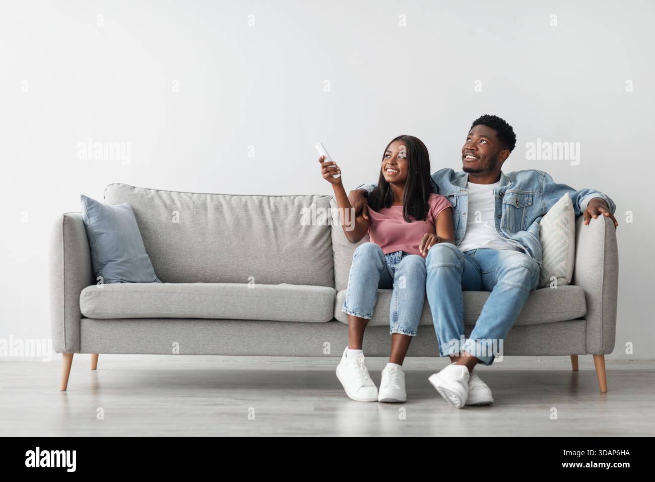 Young black woman switching on air conditioning at her home Stock Photo
