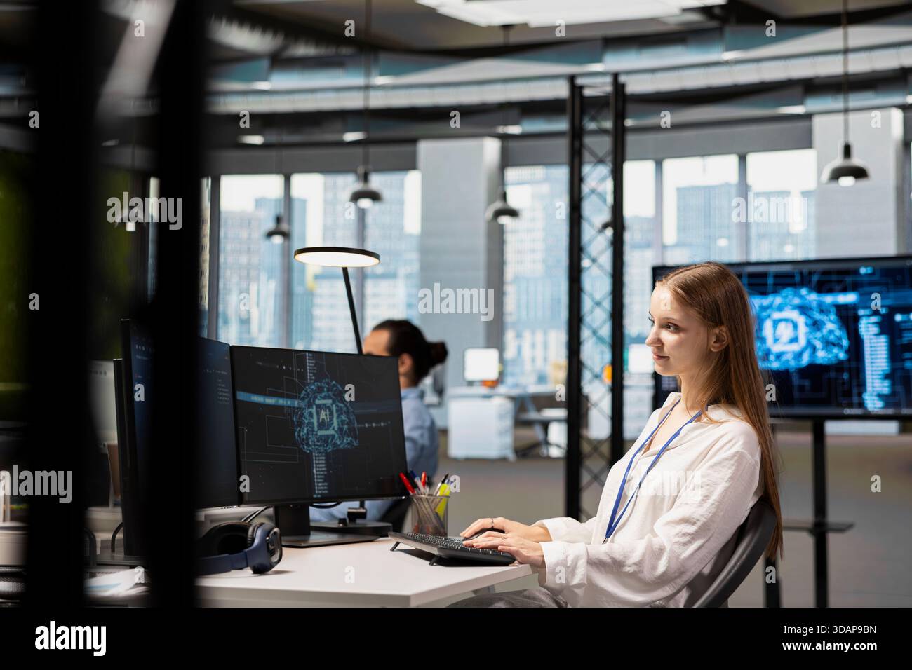 Smiling junior IT specialist writing code, developing machine learning APIs. Upbeat young female technician working in office, troubleshooting software errors using artificial intelligence tech Stock Photo