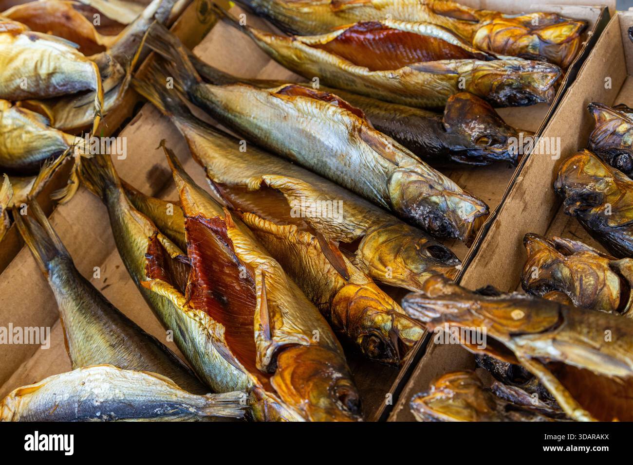Rustic Fish Market Various whole and split smoked fish displayed in cardboard boxes at ...