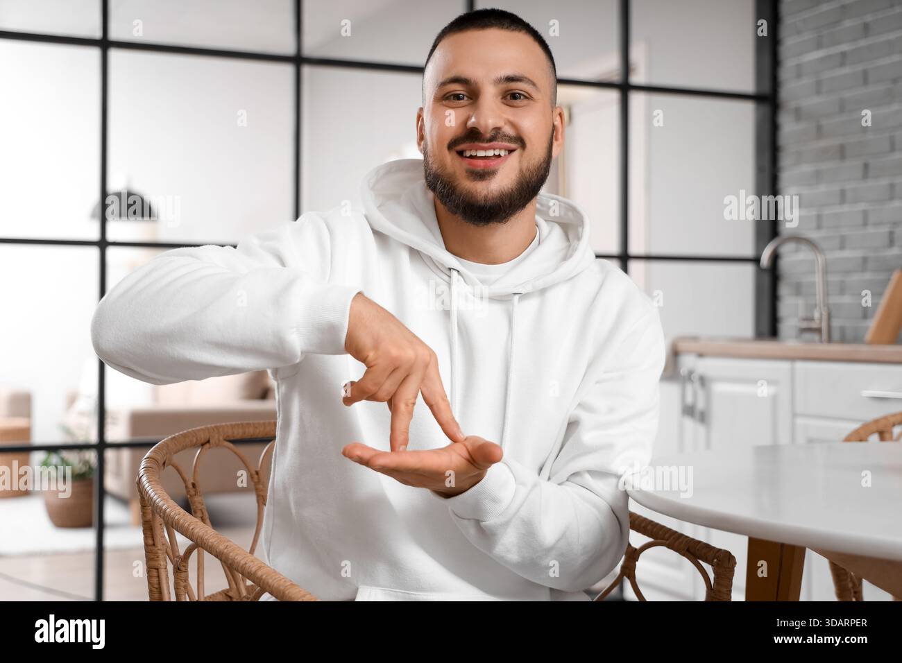 Young man using sign language in kitchen Stock Photo