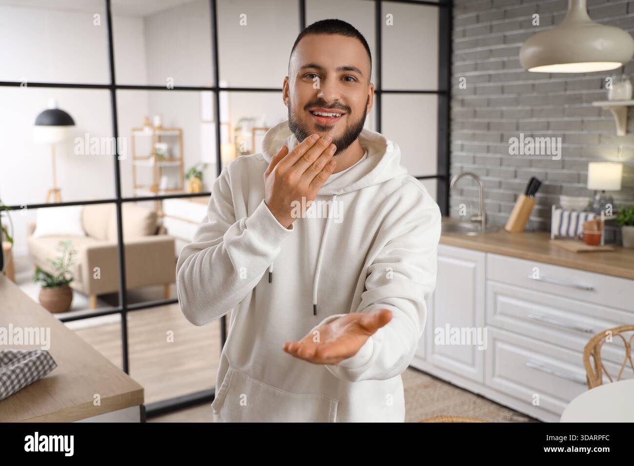 Young man using sign language in kitchen Stock Photo