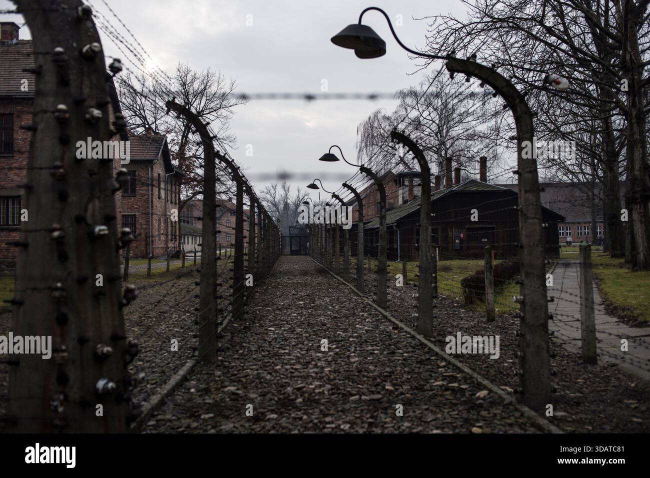 A barbed wire electric fence and barracks of prisoners are seen at the