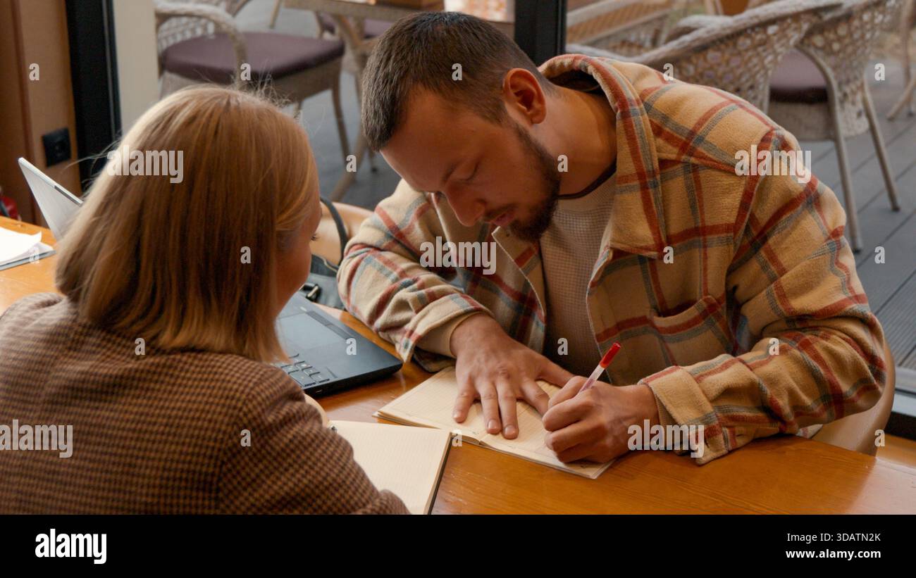 Two students focused on documents and making notes together in a cafe Stock Photo