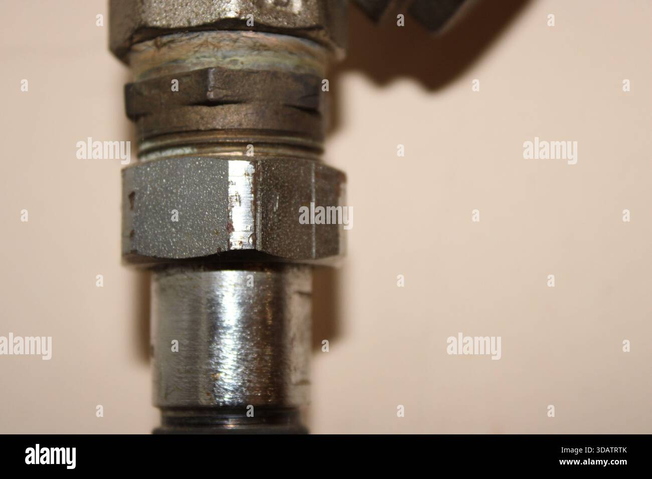 A close-up shows a metal valve with distinct threading and surface ...