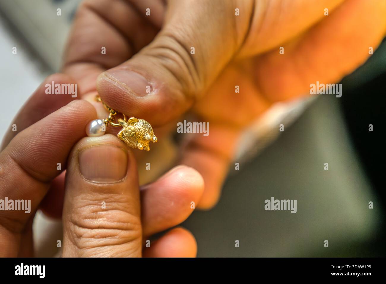 Staff at Shinju no Sato pair the pearl with a carefully selected piece of jewellery. Here, a little golden pig. In both German and Japanese, there is a saying: "Throwing pearls before swine". Shima, Mie, Japan Stock Photo