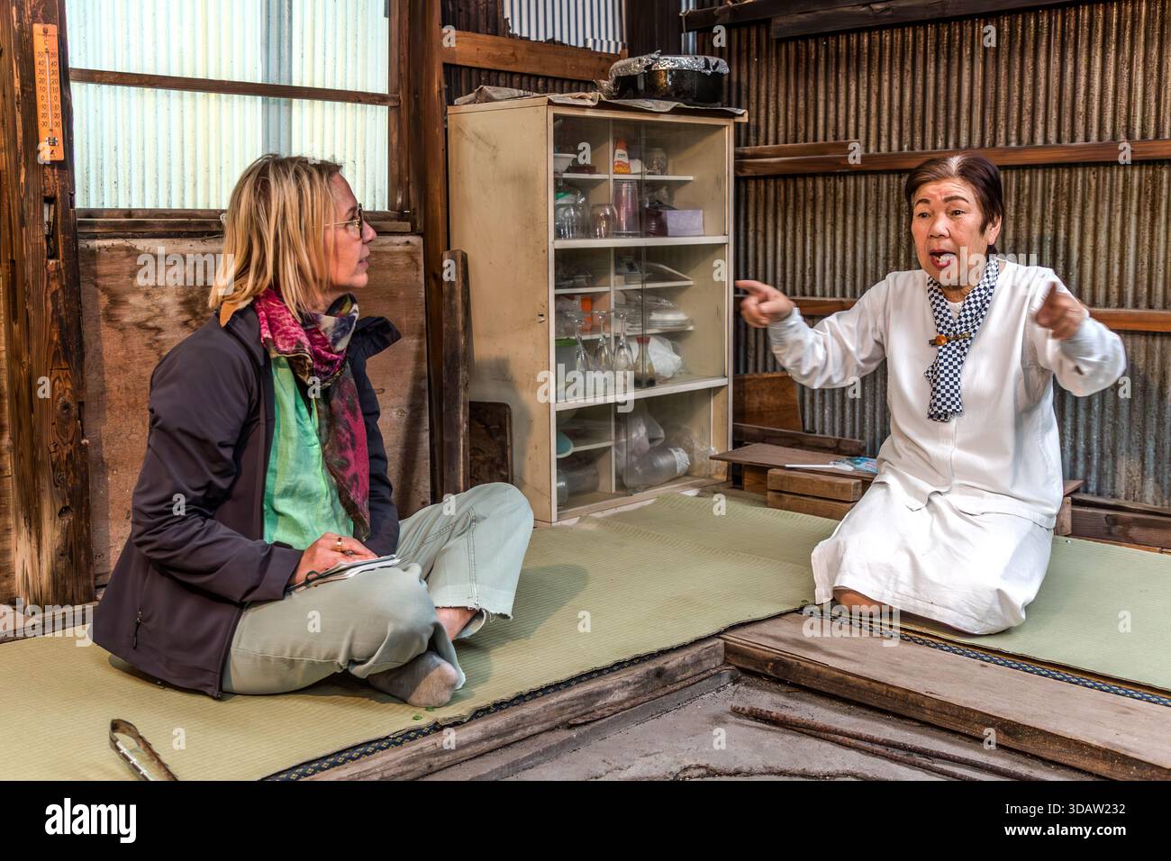 Travel journalist Angela Berg talks with Ama diver Kimiyo Hayashi in the original hut where Hayashi's mother once worked as an Ama. Shima, Mie Prefecture, Japan. Stock Photo