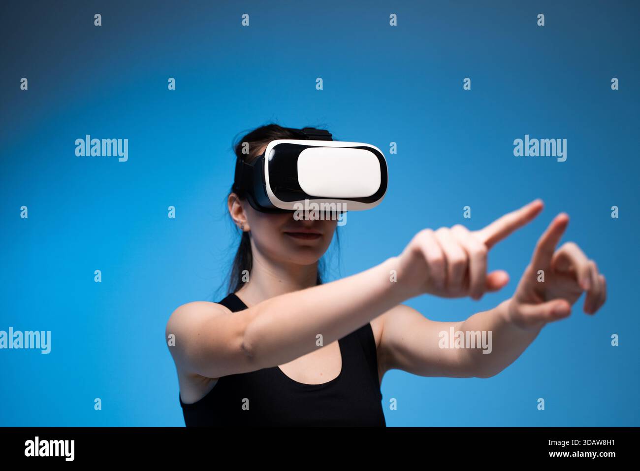 Woman immersed in VR headset experience while interacting with virtual interface using both hands Stock Photo